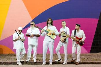 De Tierra Caliente band stands in front of colorful wall